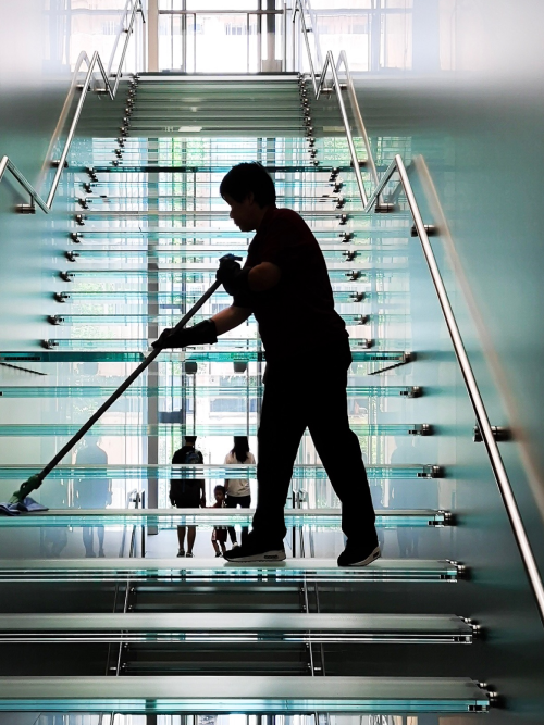 Bluebird team member cleaning a glass staircase